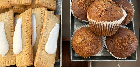 A group of strawberry pocket pastries and spiced pear muffins on metal trays. The pocket pastries are golden color with pressed edges and white icing. The muffins are dark brown topping with raw sugar and served in white liners. 